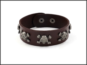 Close-up of brown leather punk bracelet featuring metallic skull studs and snap buttons