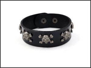 Detail of black leather punk bracelet with silver skull rivets and metal snap buttons