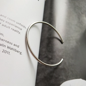 Macro detail of a minimalist S925 sterling silver open geometric bangle on a magazine