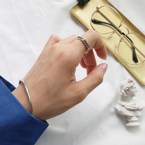 Detail of silver geometric star ring and minimalist open bangle on hand with props