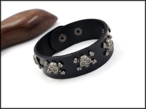 Detail of punk leather bracelet with silver skull rivets and snap closure for men