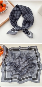 Détail d'un foulard carré en soie bleu-gris avec motifs géométriques et bordure rayée