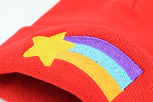 Red knit beanie hat with rainbow and yellow star embroidery in a minimalist style