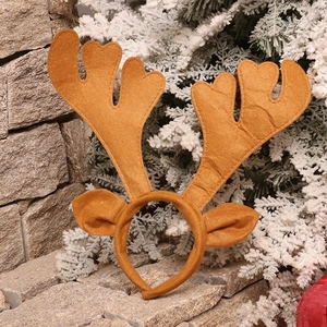 Close-up of brown plush reindeer antlers headband with ears on a snowy winter background
