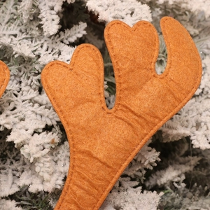 Close-up of brown felt reindeer antler decor with fine stitching on snowy pine needles