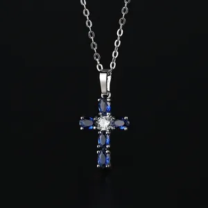 Cross necklace with blue zircon pendant and silver chain on black reflective background