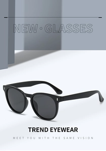 Close-up of retro oval sunglasses with black glossy frames and silver rivet details