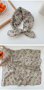 Detail of grey-green cotton scarf featuring red cherry print and purple wavy edges