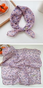 Detailed view of lightweight pink floral scarf featuring wavy edges and abstract purple prints