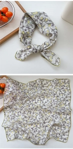 Detailed close-up of a floral cotton scarf with lemon pattern and yellow stitched hem edges
