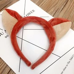 Dettaglio di un cerchietto con orecchie di gatto in peluche arancione, pizzo e campanelli