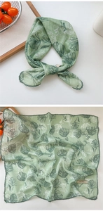 Close-up of light green floral square scarf with crochet lace trim and fabric label