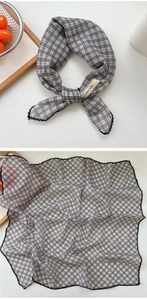 Close-up of black and grey checkered cotton scarf with elegant lace trim and woven label