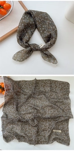 Close-up of olive green linen scarf with white floral patterns and lace edges