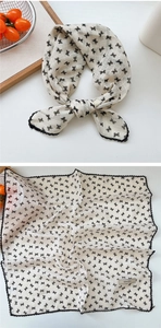 Detail of square silk scarf with black bow prints and delicate lace edge trim