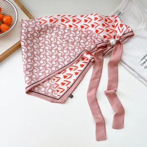 Dettaglio di sciarpa in seta a fiori con chiusura magnetica in perla e nastri in chiffon