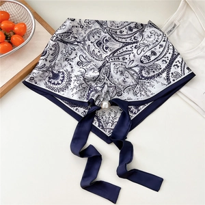 Dettaglio di sciarpa in seta stampata con motivi paisley e fibbia magnetica con perla