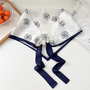 Dettaglio foulard a fiori con chiusura magnetica in perla e bordo in raso blu