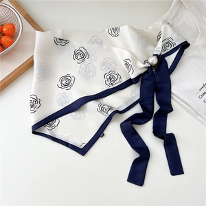 Dettaglio di un foulard in seta bianco con rose nere e chiusura magnetica con perla grande