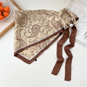 Dettaglio di foulard in seta paisley con chiusura a perla e nastri marroni lunghi