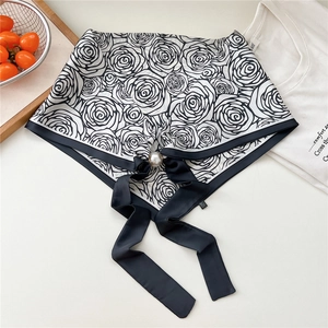 Dettaglio di foulard in seta floreale con chiusura a perla magnetica e nastri neri