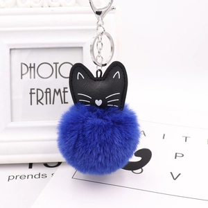 Detail of blue faux rabbit fur pompom keychain with black leather cat charm and metal ring