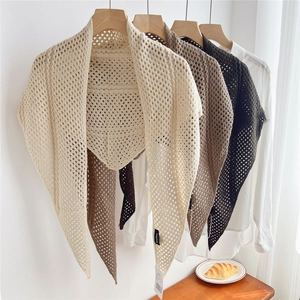 Detailed view of hollow knit crochet triangle shawls in beige and brown earth tones