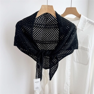 Close-up of black hollow-out knitted triangular shawl with intricate crochet mesh detail