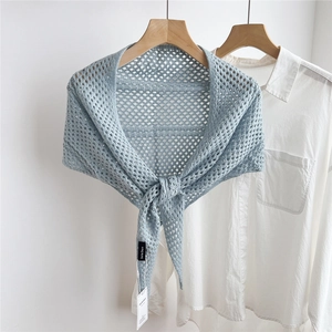 Detail of light blue hollow knit shawl featuring diamond texture and designer brand tag