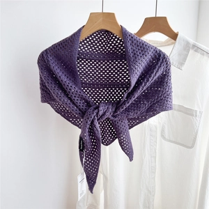 Detail of purple knitted hollow shawl with intricate mesh texture and hanging tags