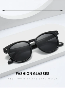 Polished black oval sunglasses with silver rivet accents on a white geometric stand
