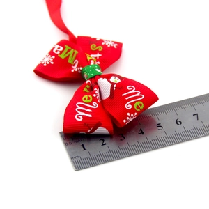 Close-up of red Christmas pet bowtie with white Merry Christmas text and snowman print