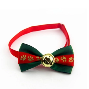 Detailed view of Christmas pet bow tie with gold bell and festive paw prints pattern
