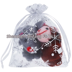 Close-up of a white organza drawstring bag with silver snowflakes and plush reindeer