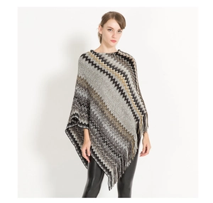 Close-up of knit poncho featuring black white and gold zig-zag patterns with fringe detail