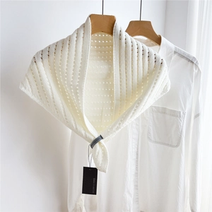 Detail of white striped hollow knit shawl showing delicate texture on wooden hanger