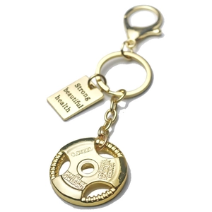 Macro detail of golden barbell weight plate keychain with engraved motivational text plates