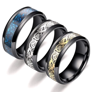 Dettaglio di tre anelli in acciaio titanio nero con intarsio blu e motivi a drago celtico