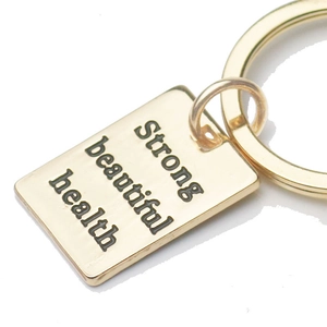 Golden boxing glove keychain with engraved metal tag featuring motivational words