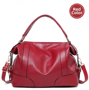 Detail view of red lychee grain leather handbag with golden hardware and long strap