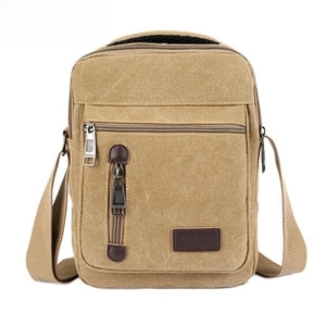 Detailed close-up of khaki canvas shoulder bag with multi-layer zippers and leather tabs