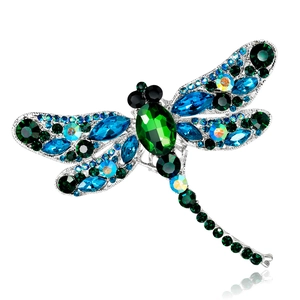 Macro shot of dragonfly brooch with green oval gemstone and blue crystal wings