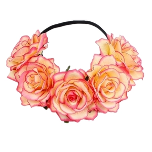 Detail of bohemian floral headband with gradient pink and orange faux roses on black elastic band