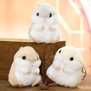 Three cute plush hamster keychains in grey, brown, and cream colors on a wooden surface