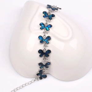 Detalle de pulsera de mariposa plateada con alas azules sobre decoración de corazón