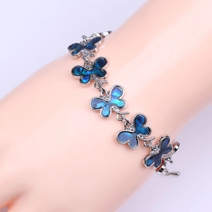 Primer plano de una pulsera de mariposa en plata con nácar de colores en la muñeca