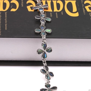 Detalle de una pulsera de trébol plateada con incrustaciones de concha de abulón