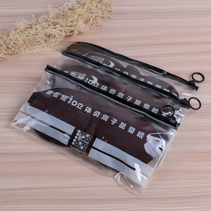 Three deep brown 3D energy eye masks with zipper bags on a light wood background