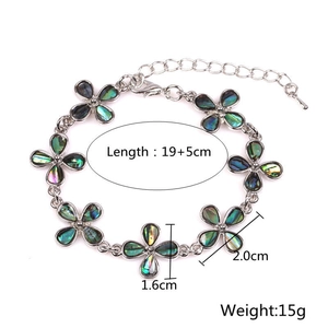 Detalle de pulsera de flor plateada con incrustación de concha de abulón y medidas