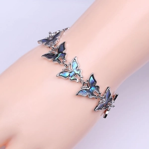Detalle de pulsera de mariposa con incrustaciones de nácar de abulón sobre la muñeca